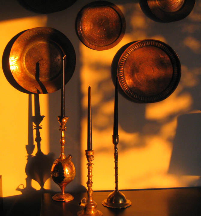 Shadowed candlesticks on tapestried wall
