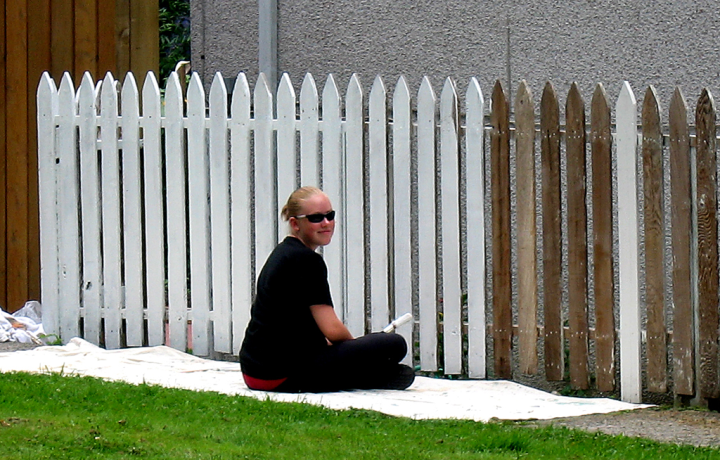 Young woman painting fence