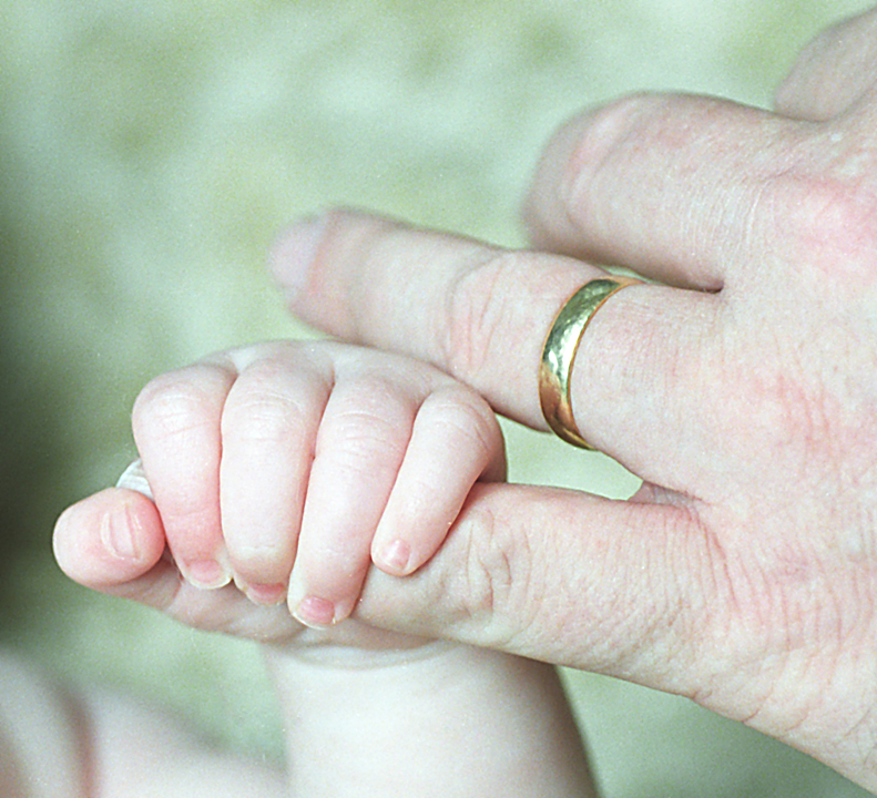 Four-month-old hand grasps fifty-year-old finger