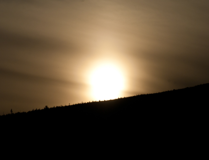 Sun setting on a wooded mountain