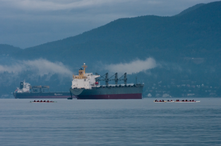 Racing rowboats in front of weighting freighters in Vancouver’s outer harbour