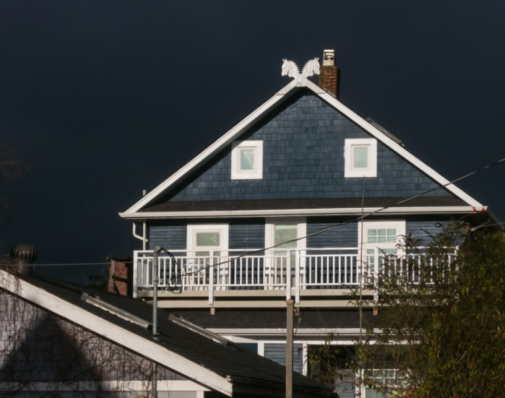 Sunlit house against dark clouds