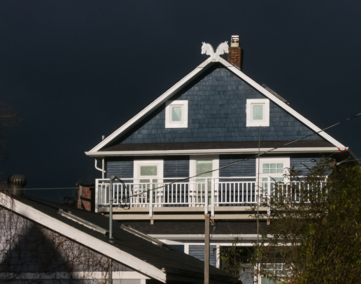 Sunlit house against dark clouds Sunlit house against dark clouds