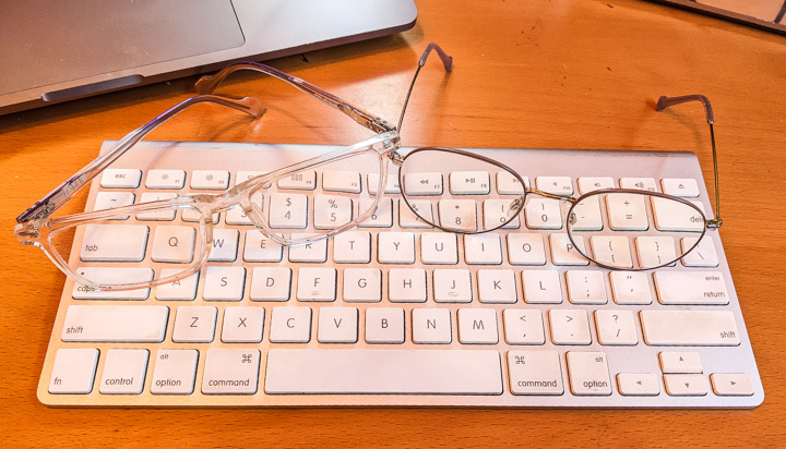 Two pairs of glasses resting on a computer keyboard