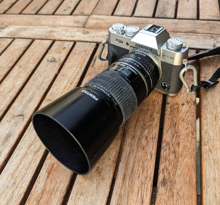 Pentax 100mm macro lens strapped on Fujifilm X-T30