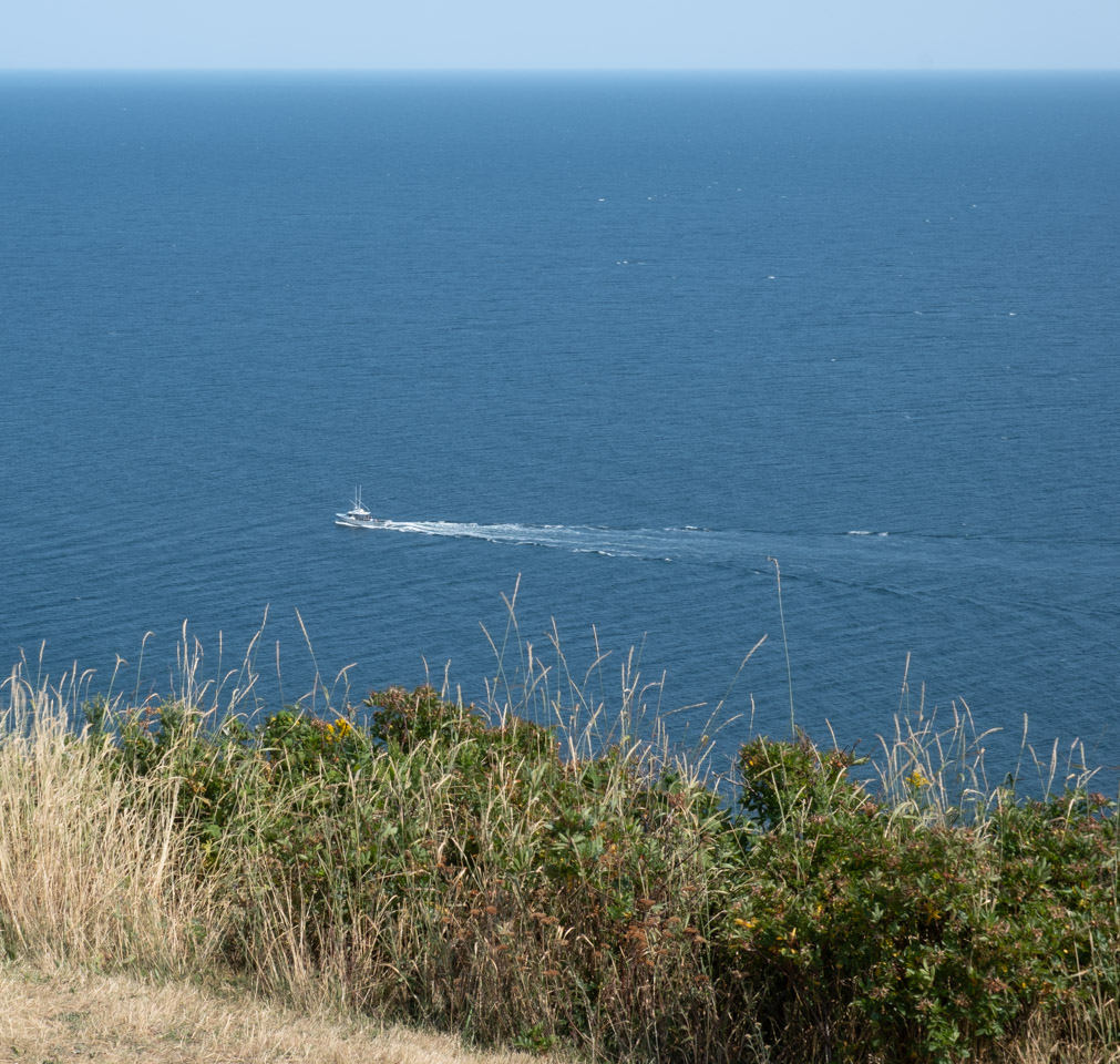 Looking down off a cliff at a tiny boat far below